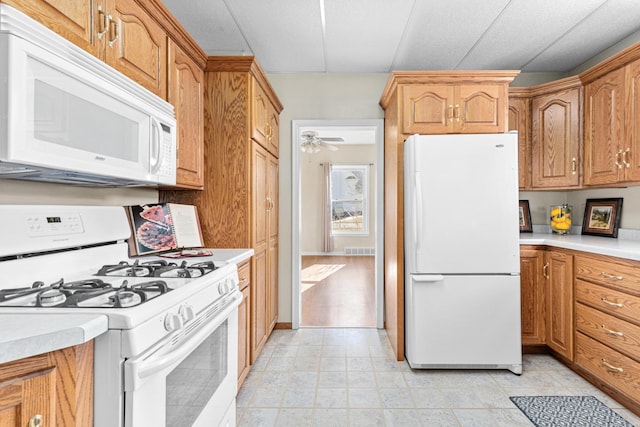 kitchen featuring brown cabinets, white appliances, a ceiling fan, visible vents, and light countertops