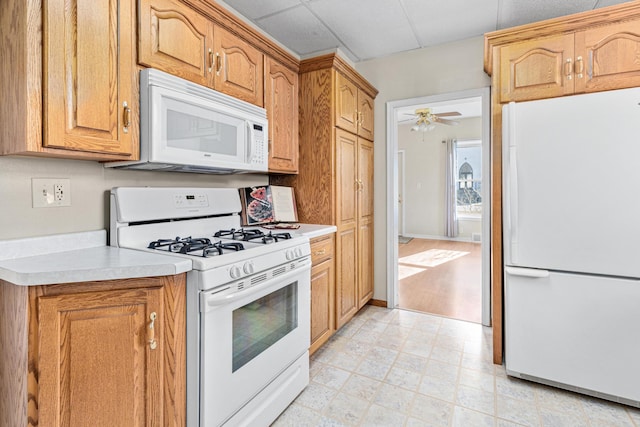 kitchen with ceiling fan, white appliances, light countertops, and a drop ceiling