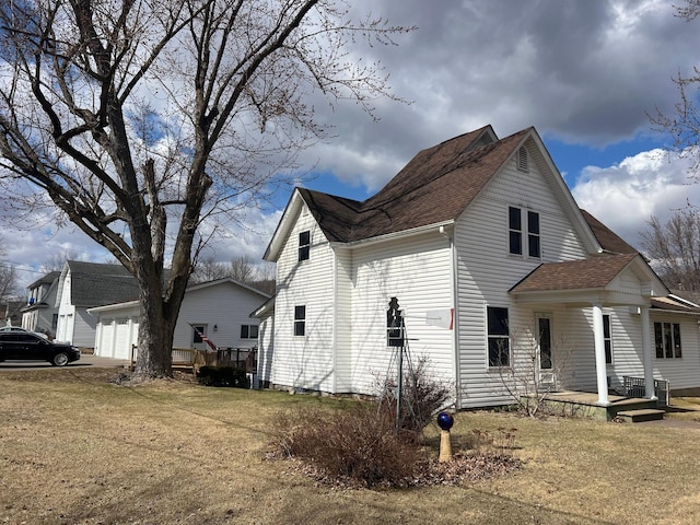 view of home's exterior with a garage, covered porch, a yard, and roof with shingles