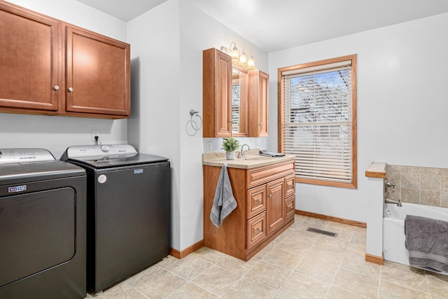 laundry room featuring light tile patterned floors, a sink, washing machine and dryer, visible vents, and baseboards