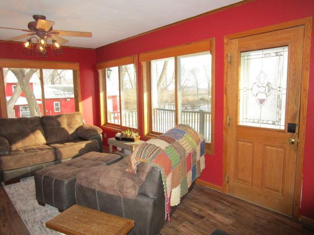 living room with plenty of natural light, a ceiling fan, wood finished floors, and baseboards