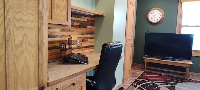 home office with built in study area, baseboards, and wood finished floors
