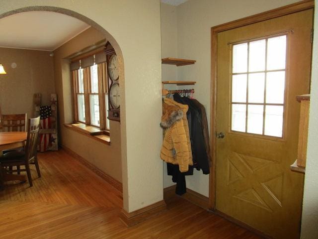 entryway featuring arched walkways, baseboards, and light wood-style flooring