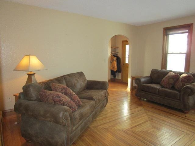 living area with arched walkways, healthy amount of natural light, and baseboards