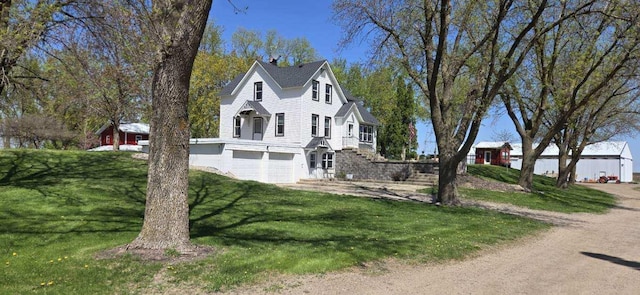 view of side of property with an attached garage, a lawn, stairs, and a chimney