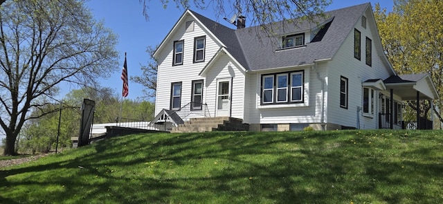 view of front of home featuring a front lawn, a chimney, and roof with shingles