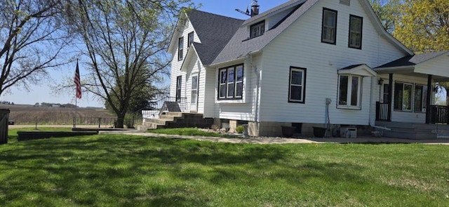 view of side of home featuring a lawn and a shingled roof