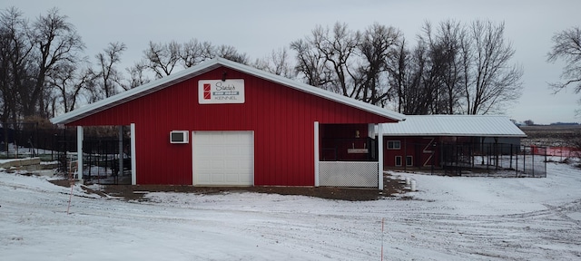snow covered structure with fence and an outbuilding