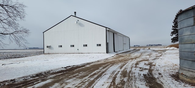 snow covered structure with an outdoor structure and a pole building