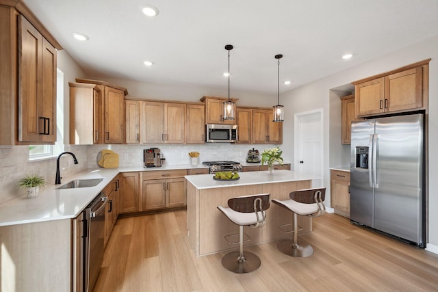 kitchen with appliances with stainless steel finishes, a sink, light wood-style floors, a kitchen island, and recessed lighting