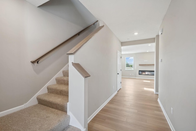 hall with stairway, light wood-type flooring, baseboards, and recessed lighting