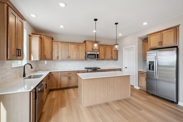 kitchen featuring appliances with stainless steel finishes, a sink, light wood-style flooring, a center island, and backsplash