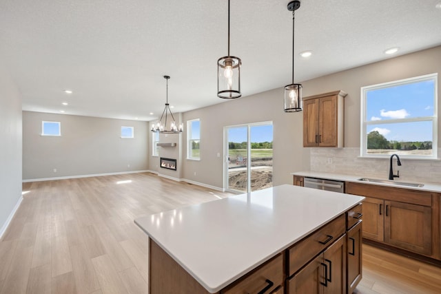 kitchen with a sink, recessed lighting, backsplash, light wood finished floors, and pendant lighting