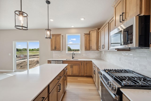 kitchen featuring appliances with stainless steel finishes, a sink, healthy amount of natural light, light countertops, and recessed lighting