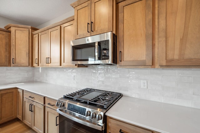 kitchen with stainless steel appliances, light countertops, and tasteful backsplash