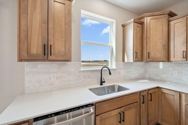 kitchen featuring stainless steel dishwasher, a sink, tasteful backsplash, and light countertops