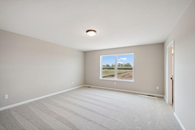 unfurnished room featuring light carpet, baseboards, and a textured ceiling