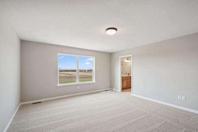 unfurnished room featuring light carpet, baseboards, and a textured ceiling