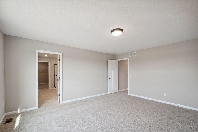 unfurnished bedroom with light colored carpet, baseboards, and a spacious closet