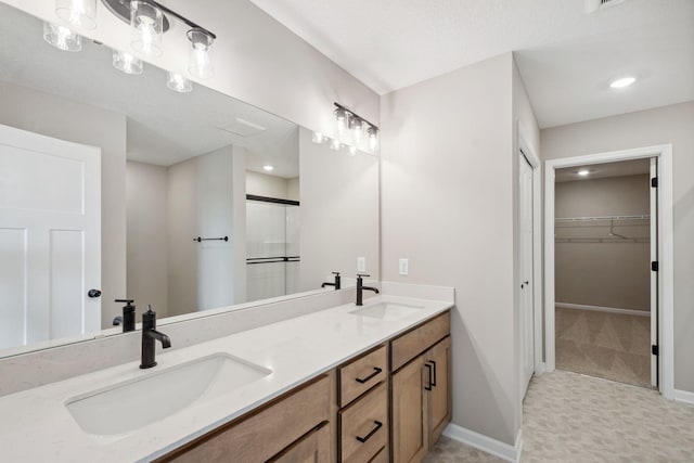 full bath featuring a stall shower, a spacious closet, baseboards, double vanity, and recessed lighting