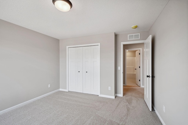 unfurnished bedroom with carpet flooring, a closet, baseboards, and a textured ceiling