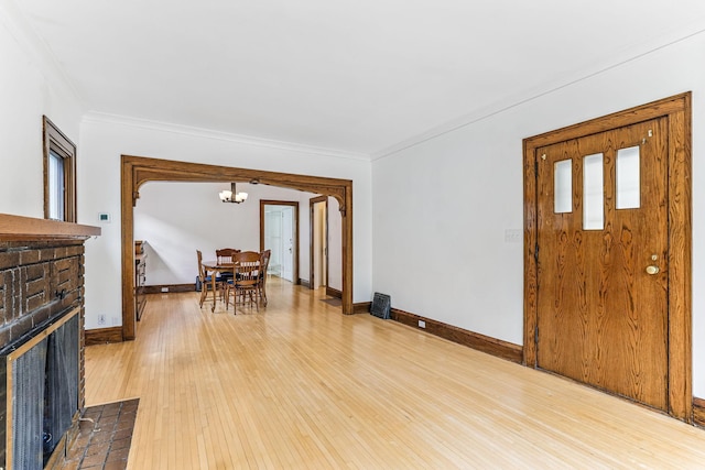 4228 Minnehaha Ave, Minneapolis, MN 55406 - foyer with a chandelier, crown molding, wood-type flooring, a brick fireplace, and baseboards