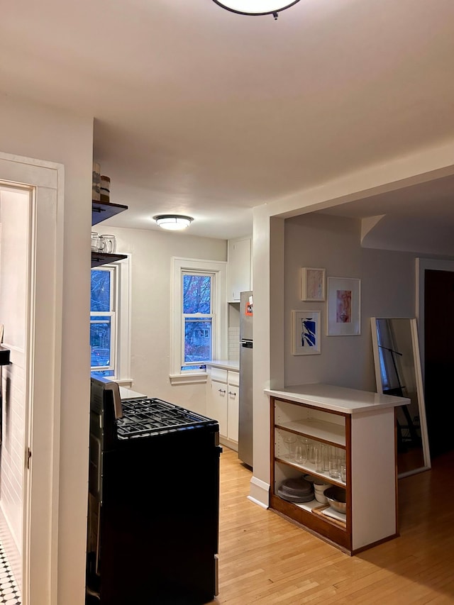 4228 Minnehaha Ave, Minneapolis, MN 55406 - kitchen featuring gas stove, white cabinets, freestanding refrigerator, light wood-type flooring, and light countertops