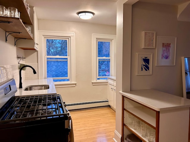 4228 Minnehaha Ave, Minneapolis, MN 55406 - kitchen featuring gas stove, a sink, baseboard heating, open shelves, and light wood-type flooring