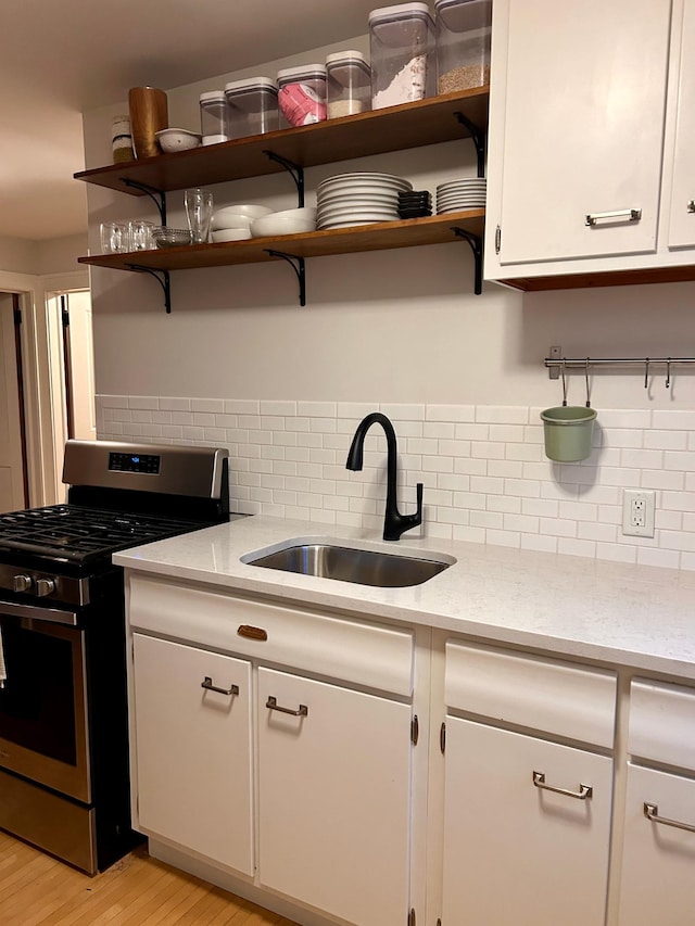 4228 Minnehaha Ave, Minneapolis, MN 55406 - kitchen featuring stainless steel gas range, a sink, open shelves, and decorative backsplash