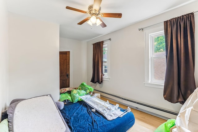 4228 Minnehaha Ave, Minneapolis, MN 55406 - bedroom featuring a baseboard radiator, multiple windows, wood finished floors, and a ceiling fan