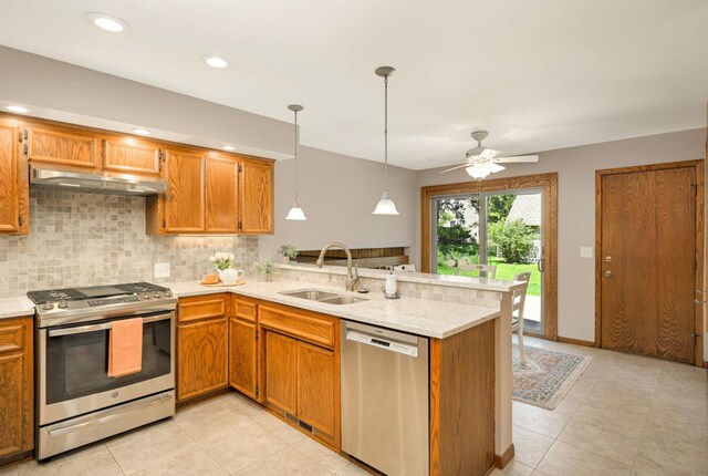 kitchen featuring stainless steel appliances, under cabinet range hood, a sink, a peninsula, and a ceiling fan