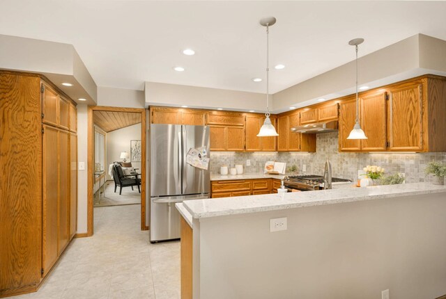 kitchen with appliances with stainless steel finishes, a peninsula, brown cabinets, under cabinet range hood, and decorative backsplash