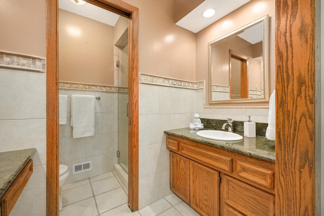 full bathroom featuring tile walls, a stall shower, vanity, tile patterned flooring, and toilet