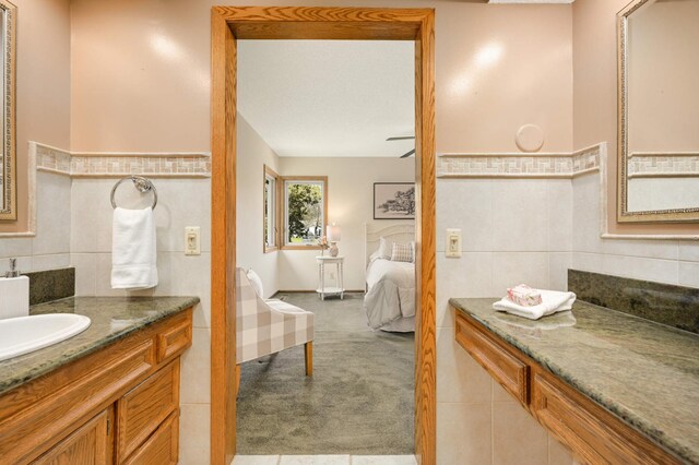 bathroom with tile walls, vanity, and ensuite bath