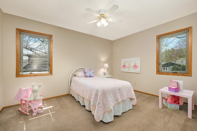 bedroom featuring multiple windows, light colored carpet, baseboards, a ceiling fan, and a textured ceiling