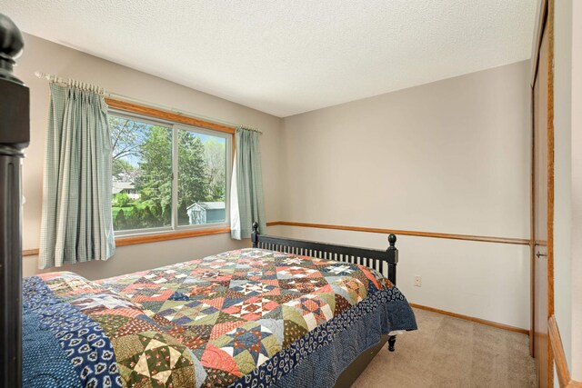 bedroom with carpet, baseboards, and a textured ceiling