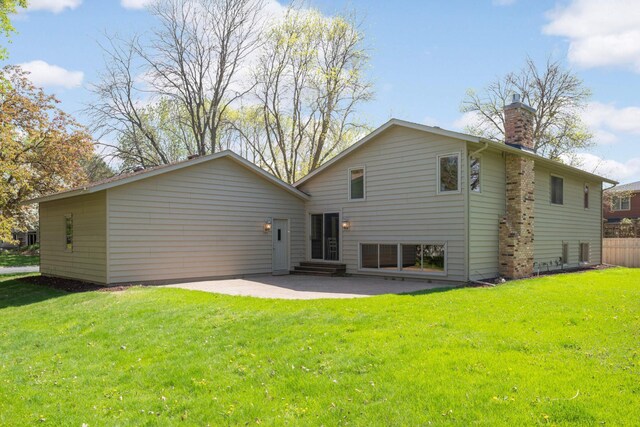 back of property with a patio area, a chimney, entry steps, and a yard