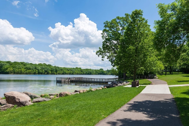 dock area featuring a yard, a water view, and a wooded view