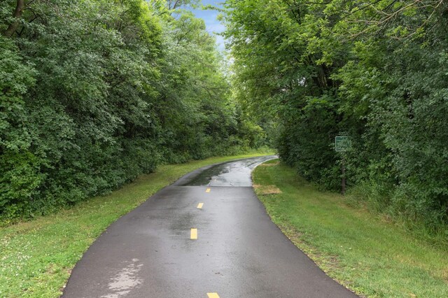 view of asphalt street featuring a view of trees