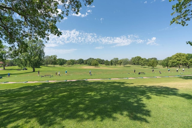 view of home's community featuring a yard, view of golf course, and view of wooded area