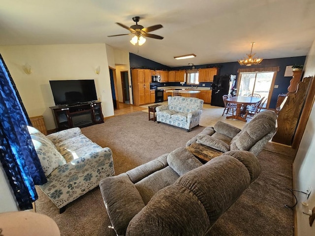 living area featuring ceiling fan with notable chandelier, light colored carpet, and vaulted ceiling