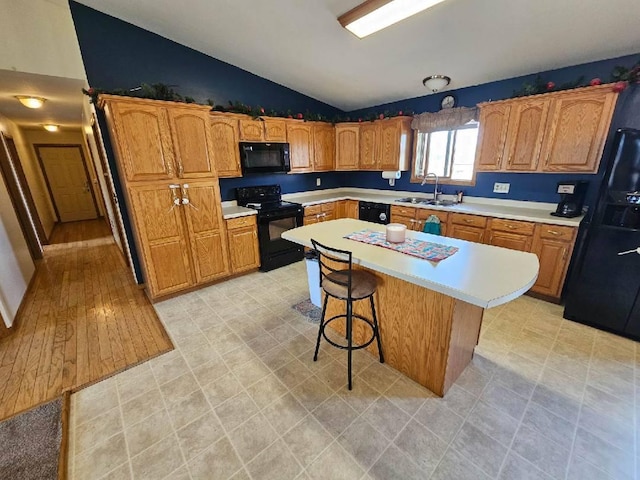 kitchen featuring light countertops, a sink, black appliances, and lofted ceiling