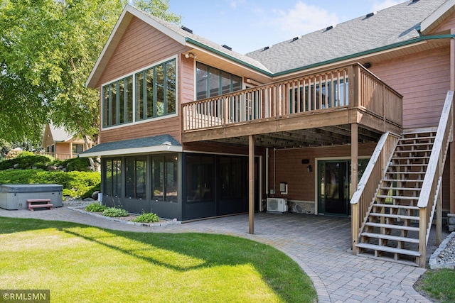 rear view of property with stairs, a hot tub, a sunroom, a patio, and a lawn