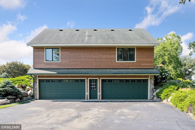 view of front of home featuring an attached garage, aphalt driveway, stone siding, and roof with shingles