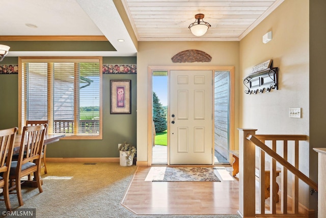 entryway featuring carpet flooring, visible vents, crown molding, baseboards, and wood ceiling