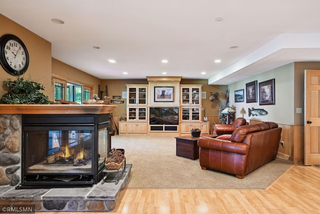 living area featuring a fireplace, a wainscoted wall, light wood finished floors, and recessed lighting