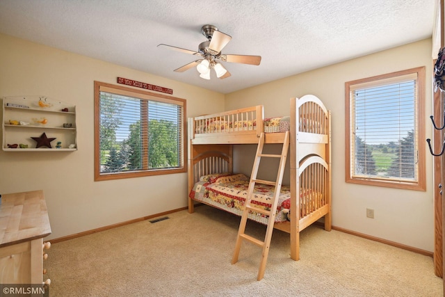 carpeted bedroom with baseboards, a textured ceiling, visible vents, and ceiling fan