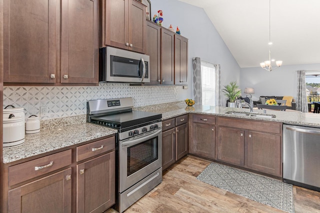 10120 189th Ave NW, Elk River, MN 55330 - kitchen with appliances with stainless steel finishes, a sink, vaulted ceiling, light wood-style flooring, and decorative backsplash