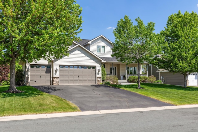 view of front of home with a porch, a front lawn, asphalt driveway, stone siding, and a garage