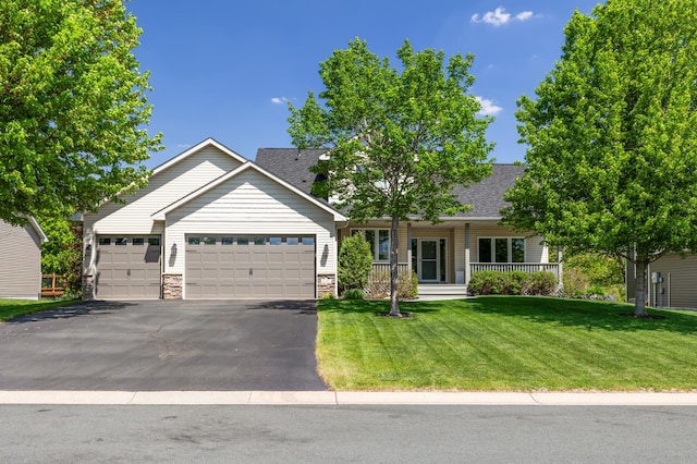 single story home featuring a garage, asphalt driveway, a front yard, covered porch, and roof with shingles